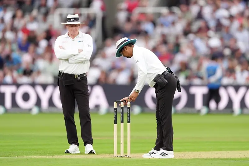 Cricket umpire watching closely from behind the stumps during a delivery